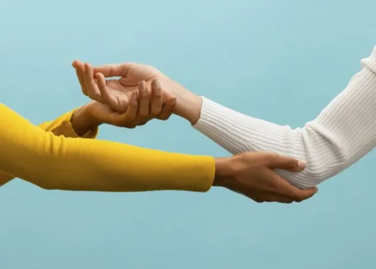 Two women shaking hands over a blue background, representing trust and support in mental health provider-patient relationship.