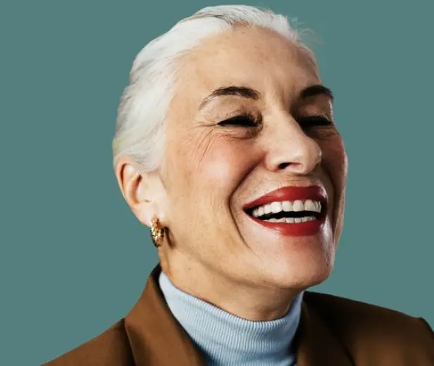A woman in a blue sweater and white hair, Smiling to showcasing the impact of mental health treatment.