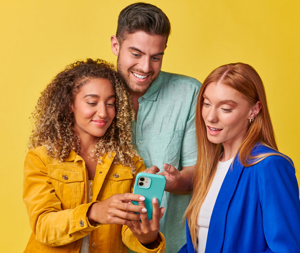 Three individuals, consisting of two girls and a boy viewing a mobile device collectively.